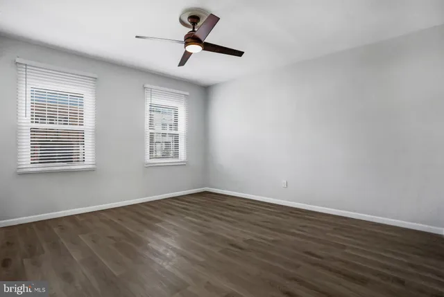 a view of empty room with wooden floor and fan