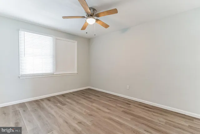 an empty room with a window and a fan