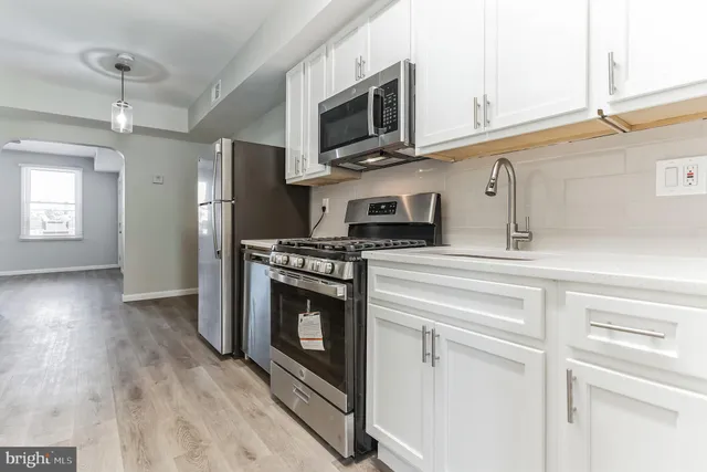 a view of an empty room with a window and a kitchen