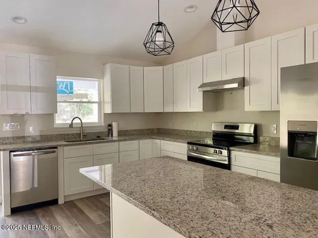 a kitchen with granite countertop a sink cabinets and stainless steel appliances