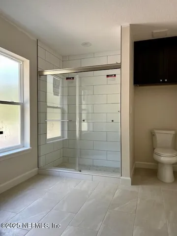 an empty room with wooden floor chandelier fan and windows