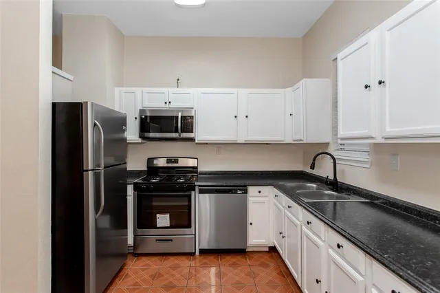 a kitchen with granite countertop white cabinets and stainless steel appliances