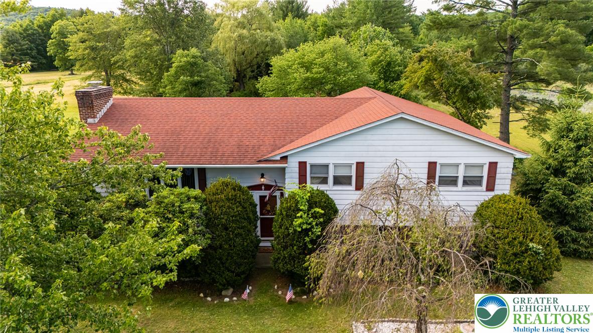 678 Interchange Road Kresgeville, PA 18333 - Photo 10 of 45 A classic ranch with a vibrant red roof nestled among verdant trees and lush landscaping.