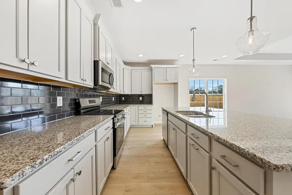 a large kitchen with stainless steel appliances granite countertop a sink a stove and a wooden cabinets