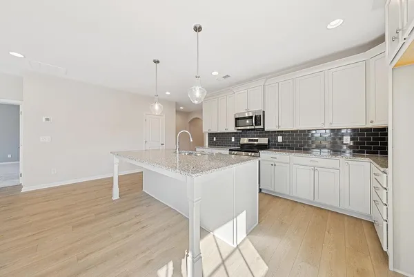 a kitchen with stainless steel appliances kitchen island granite countertop a sink a microwave and cabinets