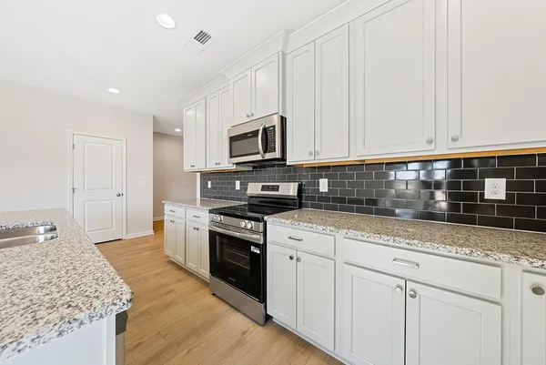 a kitchen with granite countertop white cabinets and stainless steel appliances
