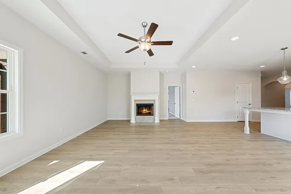 a view of a livingroom with a fireplace a ceiling fan and window