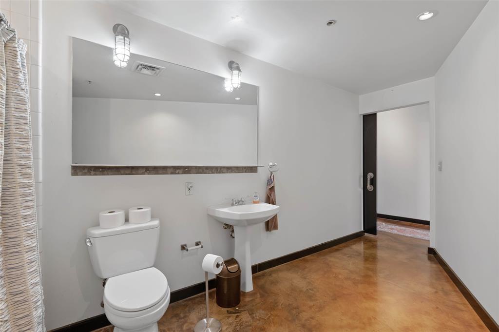 1122 Jackson Street, Unit 313 Dallas, TX 75202 - Photo 18 of 27 a bathroom with a toilet a sink and a mirror
