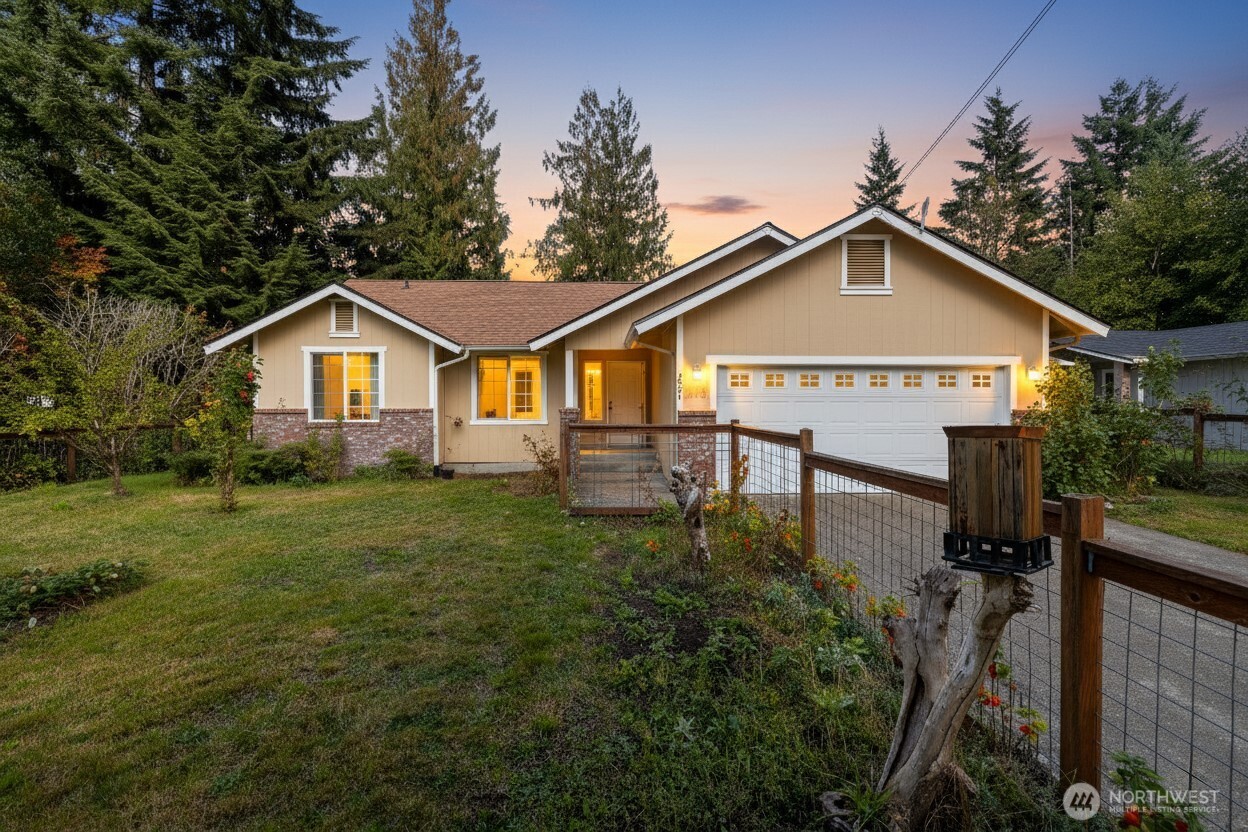 a view of a yard in front of a house with plants and large tree