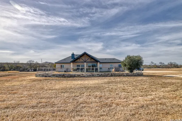 a view of a house with a yard and a large tree in front of it