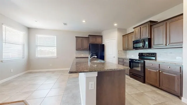 a kitchen with kitchen island granite countertop a stove sink and microwave