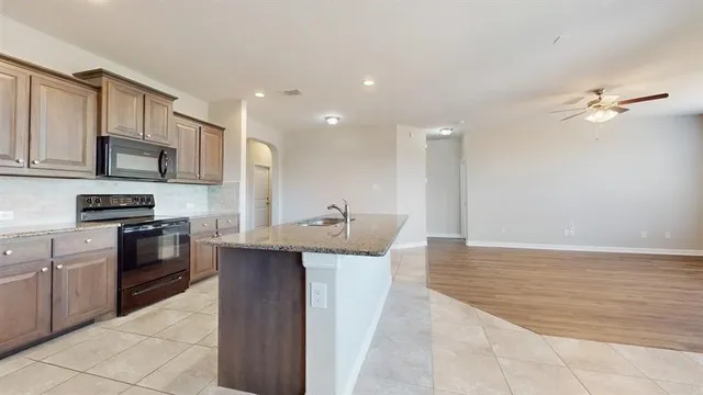 a kitchen with kitchen island granite countertop a sink appliances cabinets and a counter top space