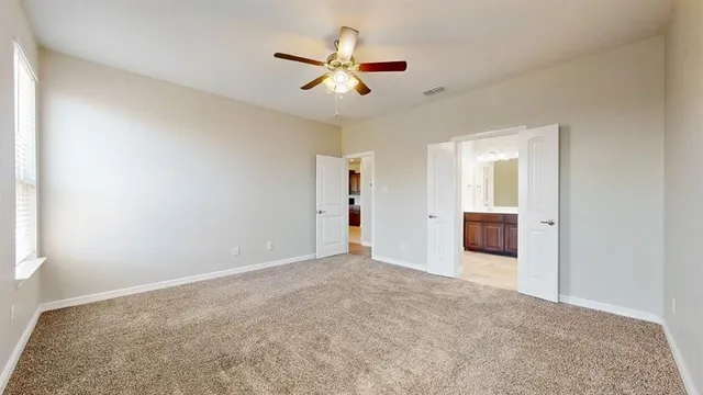 a view of a livingroom with a ceiling fan & windows