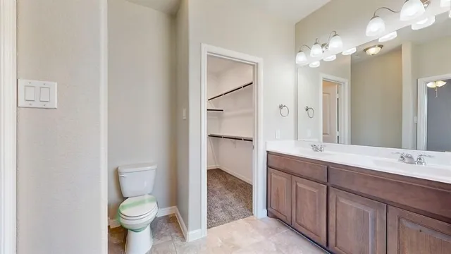 a bathroom with a toilet sink double vanity and a mirror