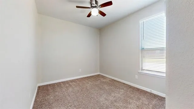 an empty room with a window and a fan