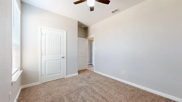 an empty room with a ceiling fan and a window
