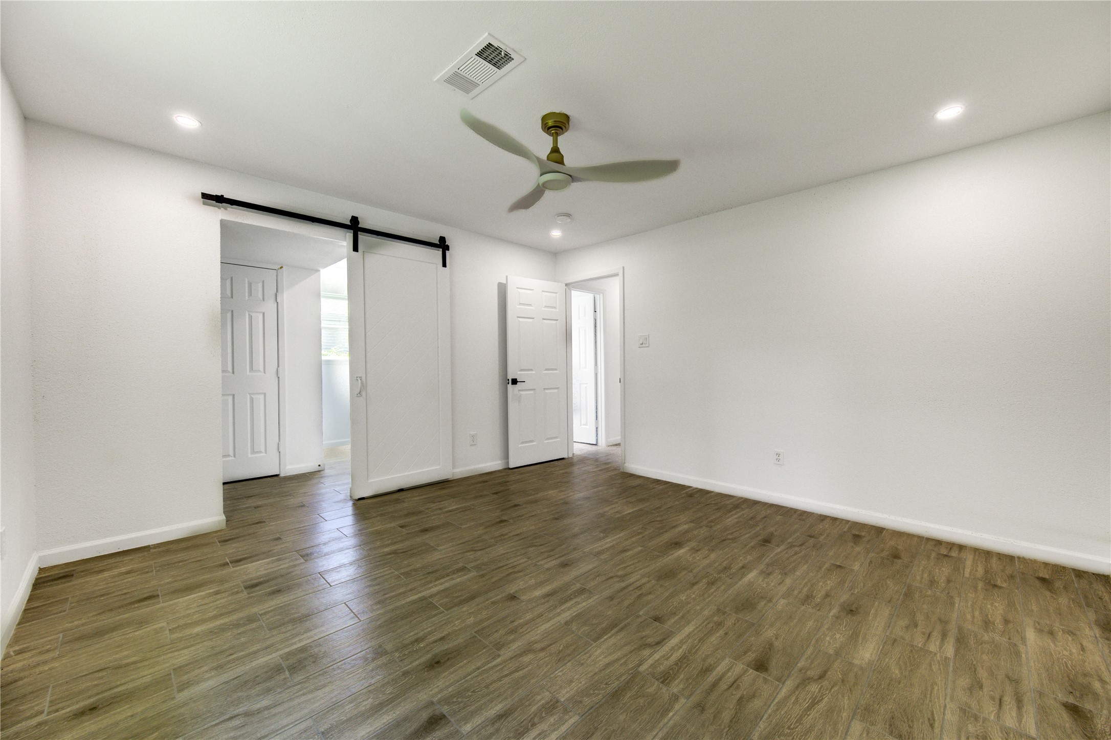 5411 Logston Lane Spring, TX 77389 - Photo 31 of 50 Spacious, light-filled room featuring elegant wood flooring, a sleek ceiling fan, and a modern barn door for style and function.