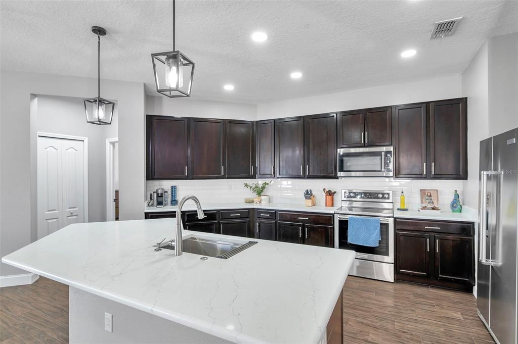 7523 Tangle Brook Boulevard Gibsonton, FL 33534 - Photo 2 of 35 a kitchen with stainless steel appliances kitchen island a sink a stove a refrigerator and cabinets