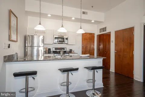 a kitchen with stainless steel appliances a kitchen island a stove a table and chairs in it