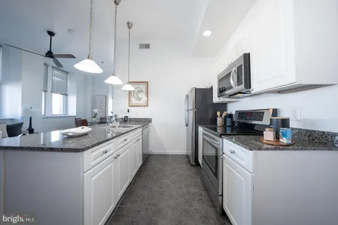 a kitchen with stainless steel appliances granite countertop a sink a stove and a wooden floors