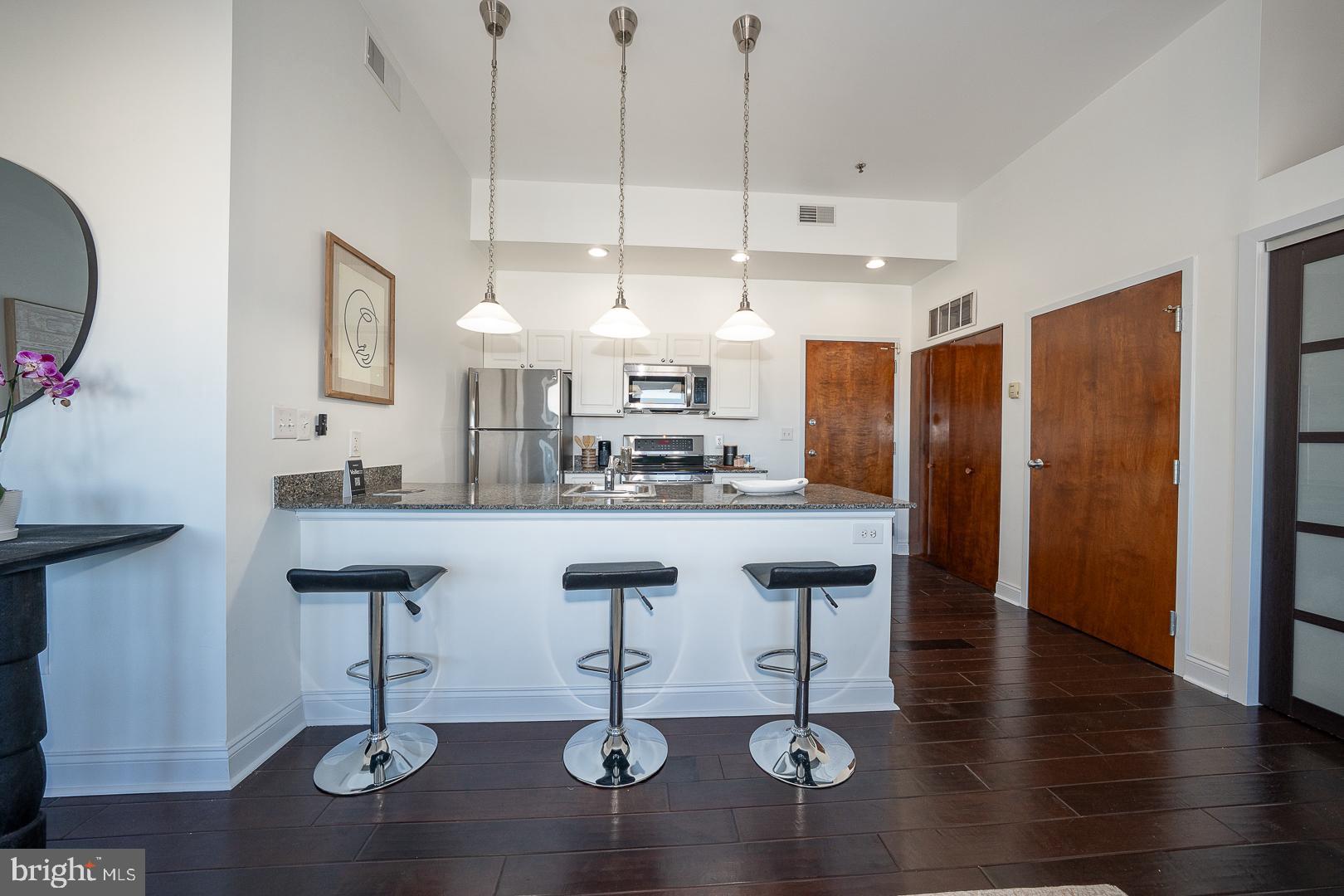 1001 Chestnut Street, Unit 705E Philadelphia, PA 19103 - Photo 19 of 36 a kitchen with stainless steel appliances kitchen island granite countertop a table chairs in it and wooden floors