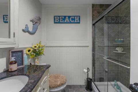 a bathroom with a granite countertop sink a toilet and shower