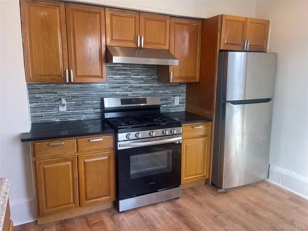 a kitchen with granite countertop a refrigerator stove and cabinets