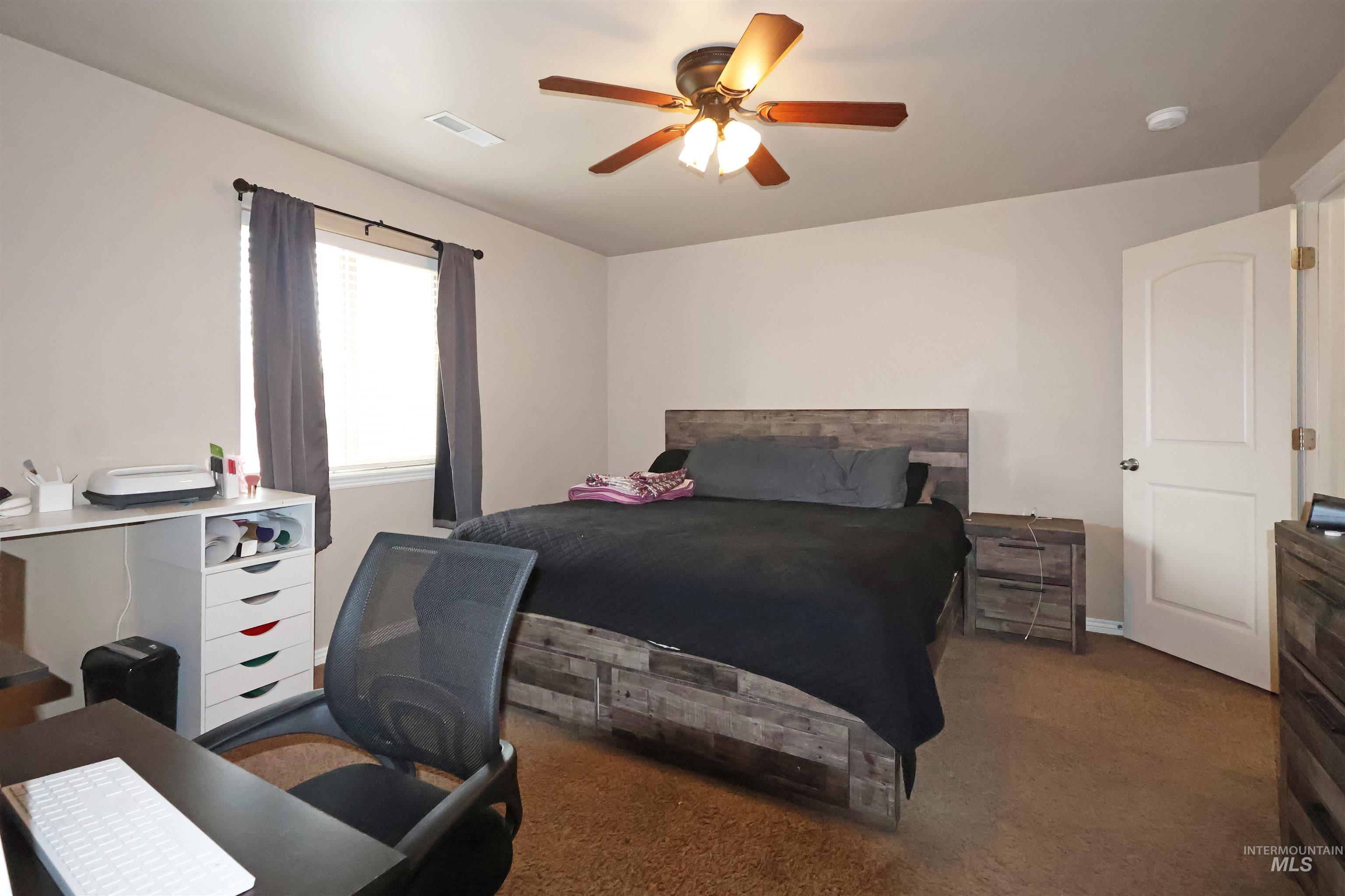 717 South B Street Rupert, ID 83350 - Photo 12 of 13 Bedroom featuring a ceiling fan, dark carpet, and a desk