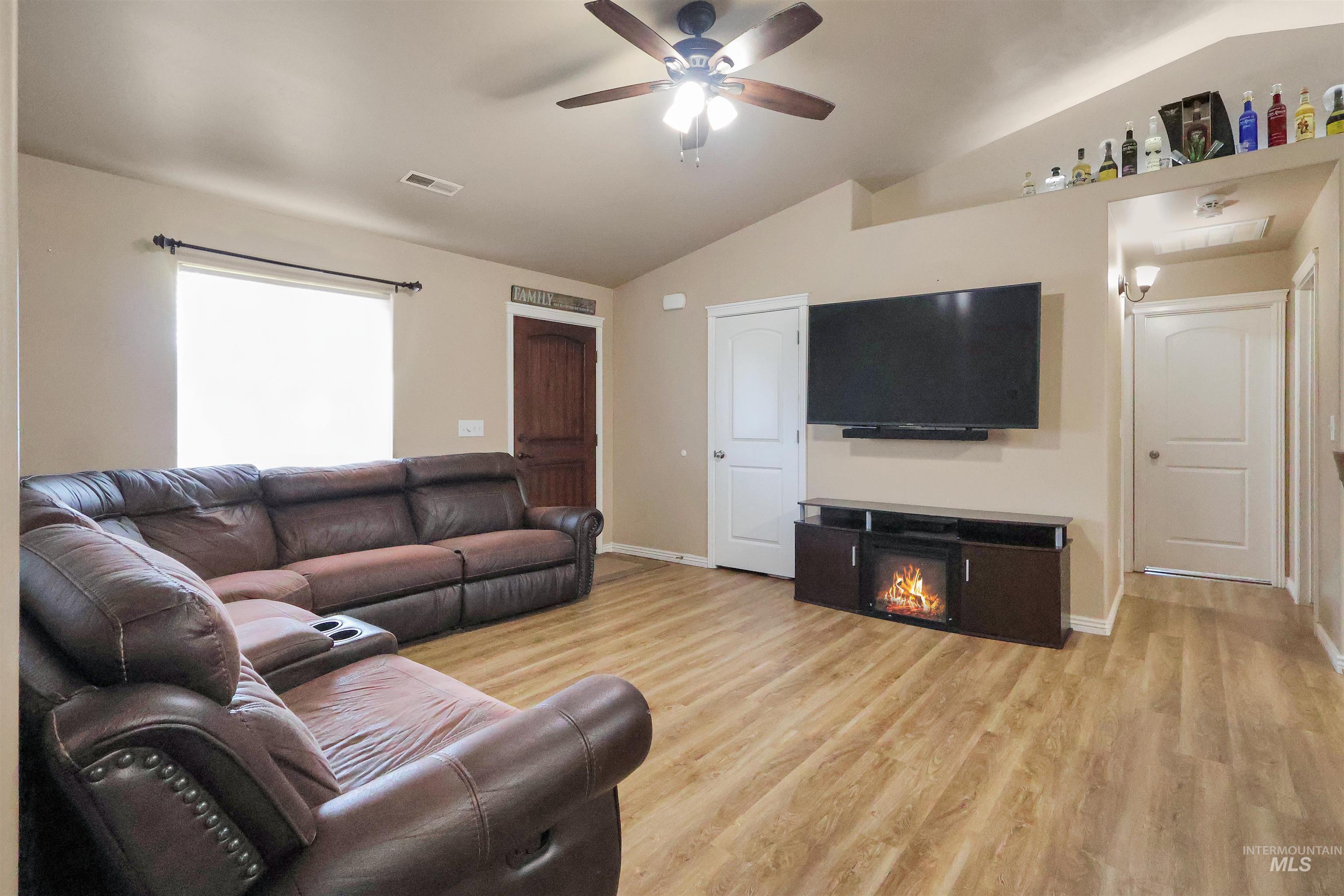 717 South B Street Rupert, ID 83350 - Photo 3 of 13 Living room featuring lofted ceiling, light wood-type flooring, a glass covered fireplace, and ceiling fan