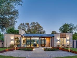 5736 Stonegate Road Dallas, TX 75209 - Photo 2 of 29 Modern architecture with a metal roof, stone and wood-panel accents, expansive windows, and integrated exterior lighting