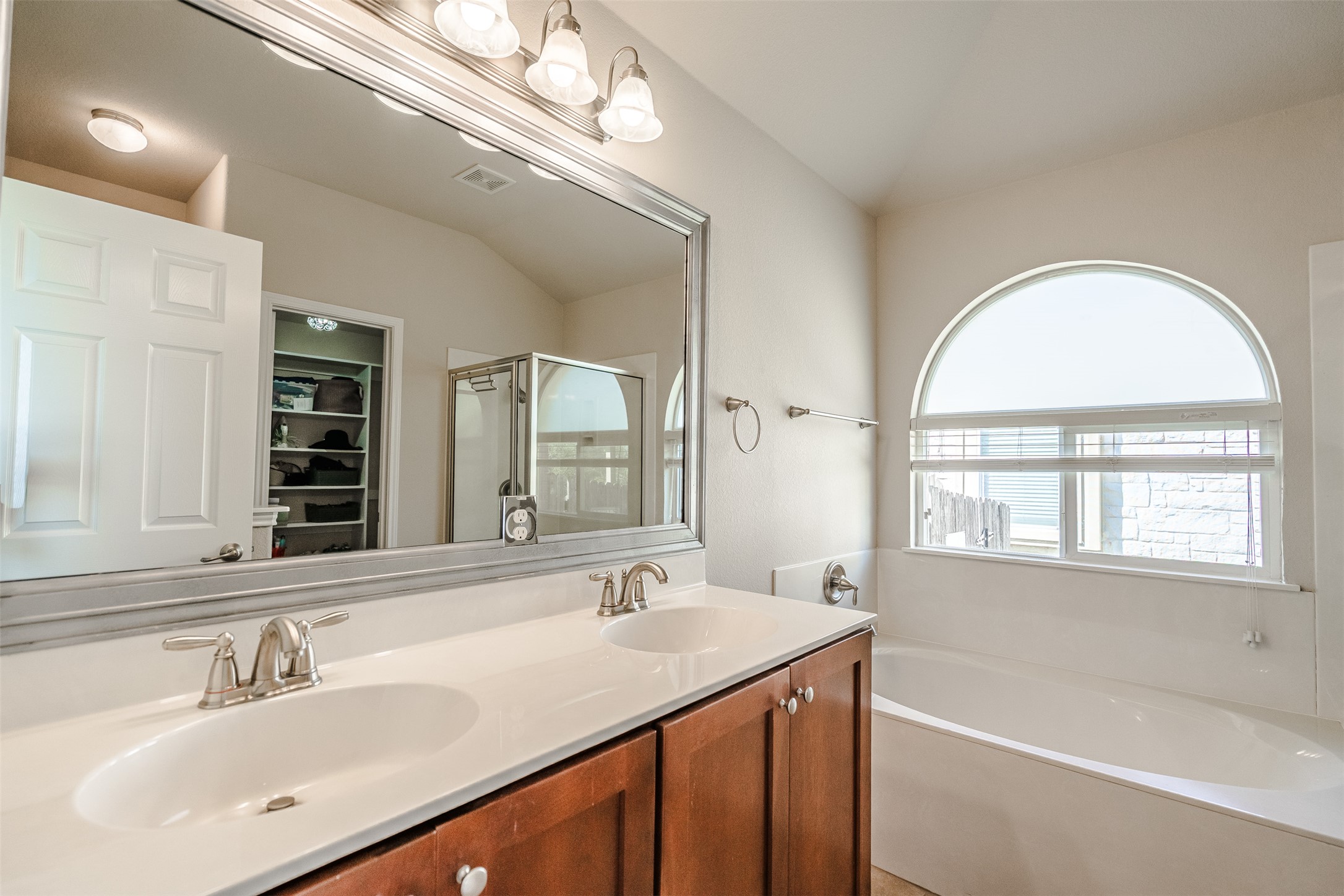 2404 Christoff Loop Austin, TX 78748 - Photo 12 of 24 Bathroom with double vanity, vaulted ceiling, a garden tub, a walk in closet, and a stand up shower