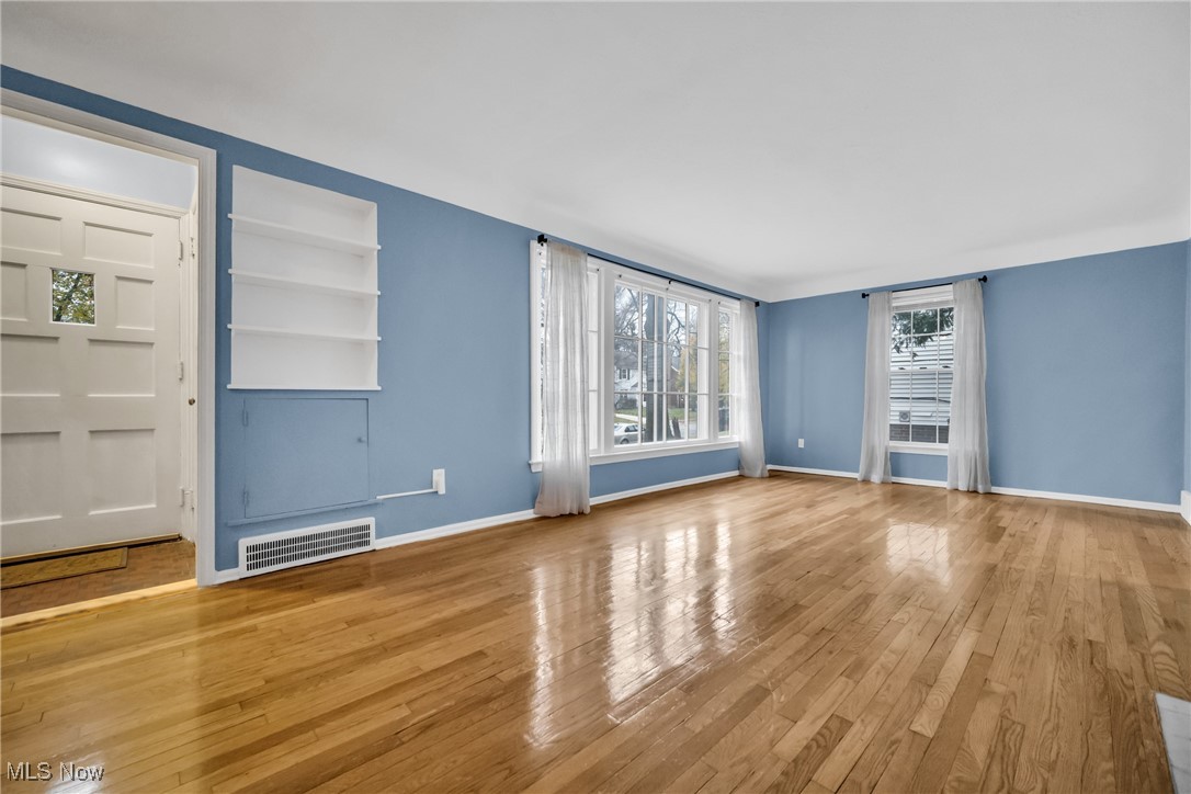 1605 Laclede Road Cleveland, OH 44121 - Photo 5 of 40 Unfurnished living room with baseboards, visible vents, built in features, and wood-type flooring