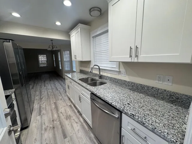 a kitchen with granite countertop a sink a stove and cabinets