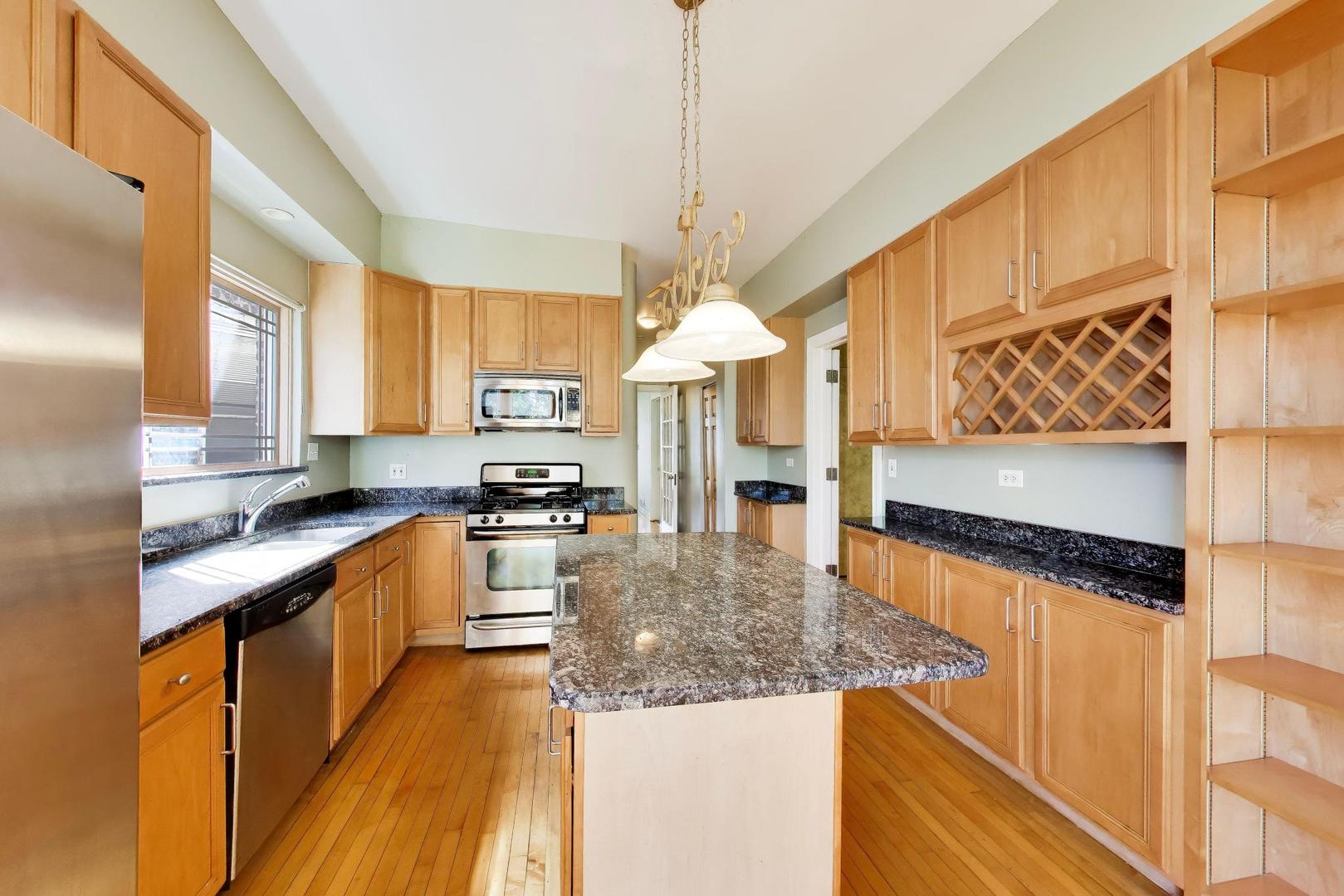 2629 North Troy Street Chicago, IL 60647 - Photo 7 of 16 a kitchen with stainless steel appliances granite countertop a sink a stove and a wooden floors