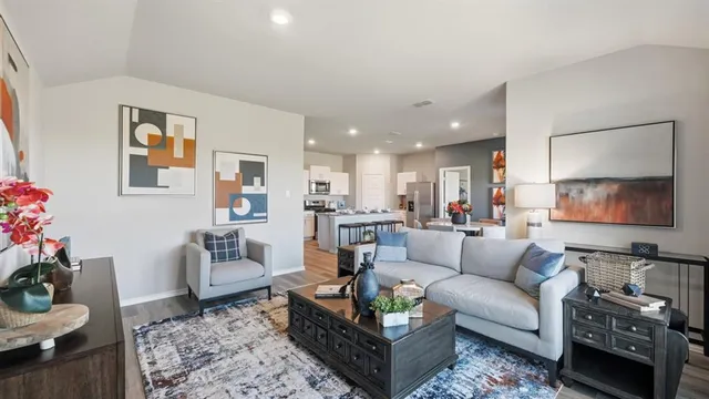 a living room with stainless steel appliances furniture a dining table and a refrigerator