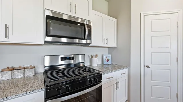 a kitchen with stainless steel appliances granite countertop a refrigerator a stove a sink a dining table and chairs with wooden floor