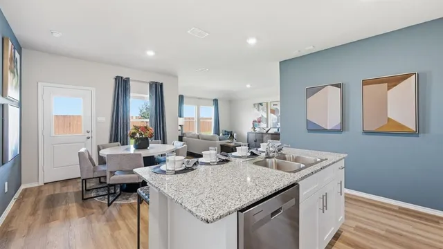 a kitchen with stainless steel appliances kitchen island granite countertop a sink a stove a table and chairs