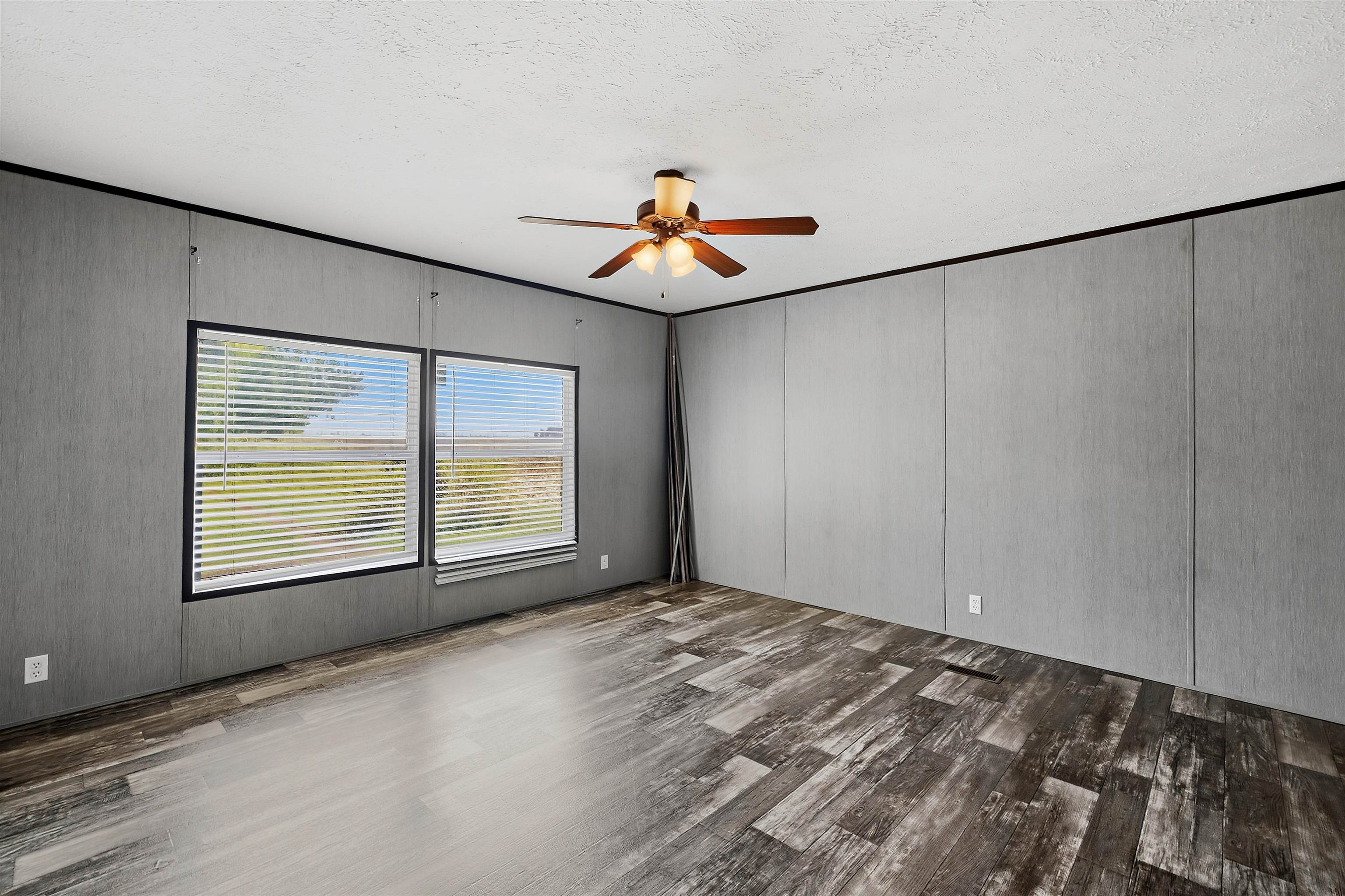 664 Rialto Road Covington, TN 38019 - Photo 19 of 24 Wood-finish flooring, two large windows with blinds, ceiling fan with integrated lighting, and textured wall panels