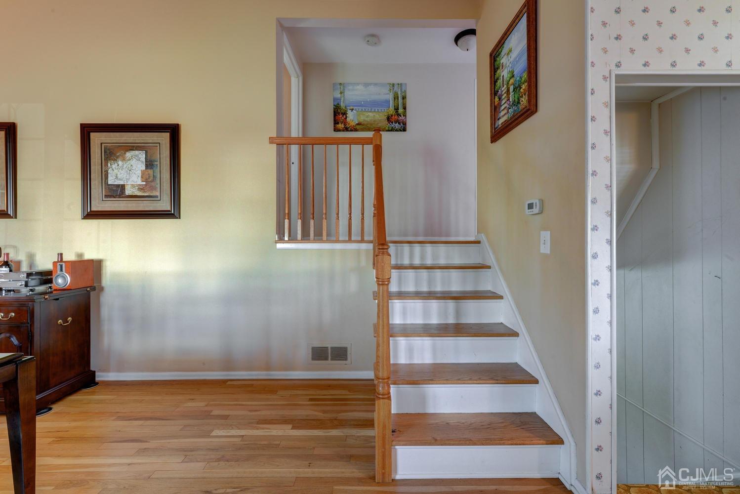 85 Albemarle Road Colonia, NJ 07067 - Photo 6 of 29 a view of a hallway with paintings on the wall and wooden floor
