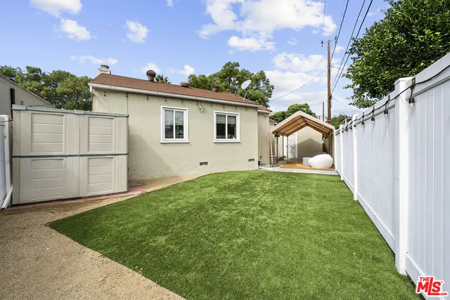 a view of backyard of house with wooden fence