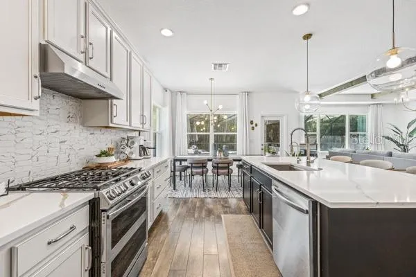 a kitchen with stainless steel appliances kitchen island granite countertop a table chairs sink and cabinets