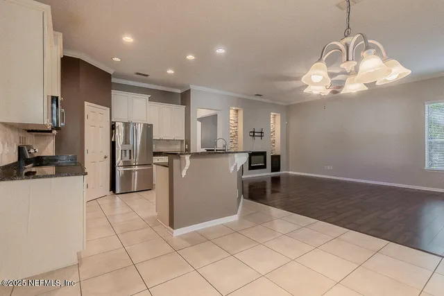 a kitchen with stainless steel appliances granite countertop white cabinets a window and a sink