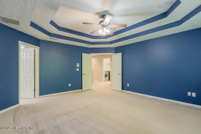 a view of an empty room with a chandelier fan