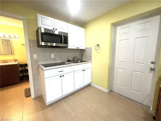 a white kitchen with a sink and a microwave