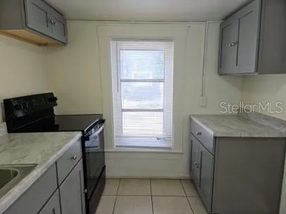 a utility room with a sink a cabinetry and a window