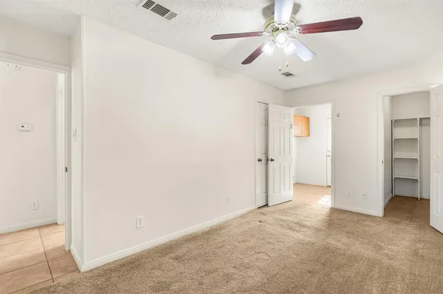 an empty room with chandelier fan and closet