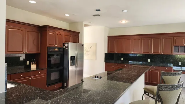 a kitchen with kitchen island granite countertop wooden cabinets a refrigerator and a sink