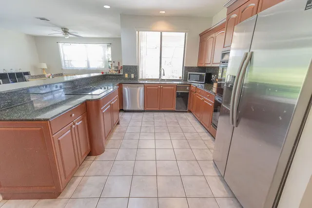 a large kitchen with stainless steel appliances granite countertop a sink a counter top space cabinets and a window