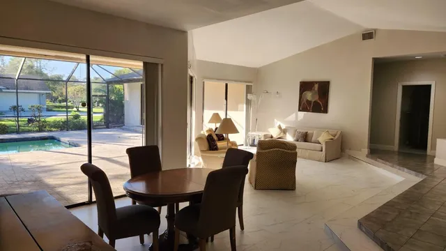 a dining room with furniture and large windows