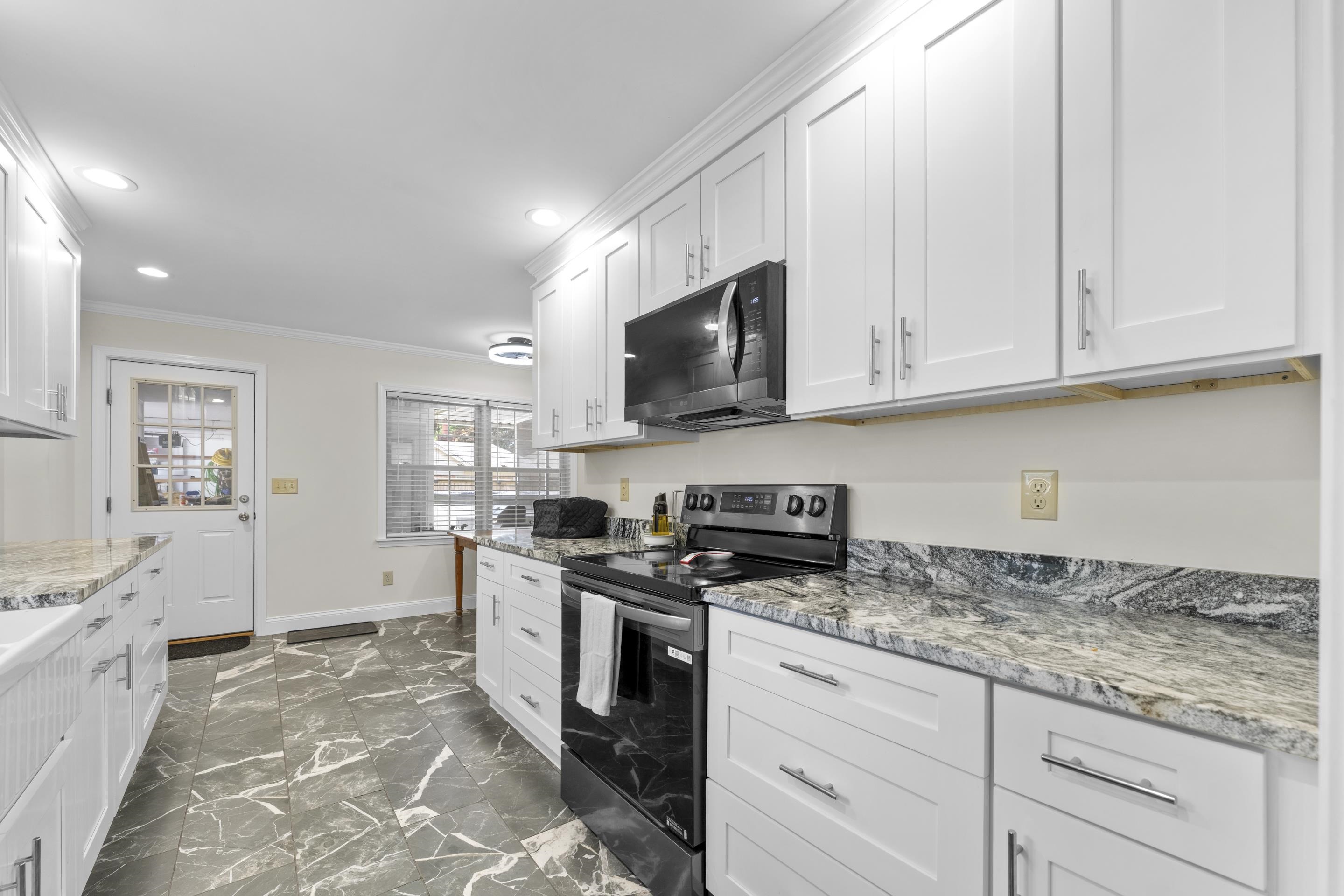 2218 Riverdale Road Germantown, TN 38138 - Photo 7 of 40 Renovated kitchen showcases abundant cabinet storage, granite countertops, farmhouse sink, and modern finishes designed for both function and style.